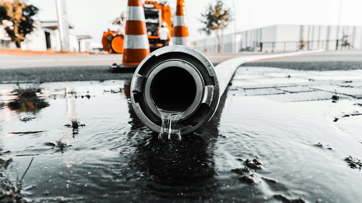 Wasser, das aus einem grauen Rohr kommt, als Darstellung eines Lecks.